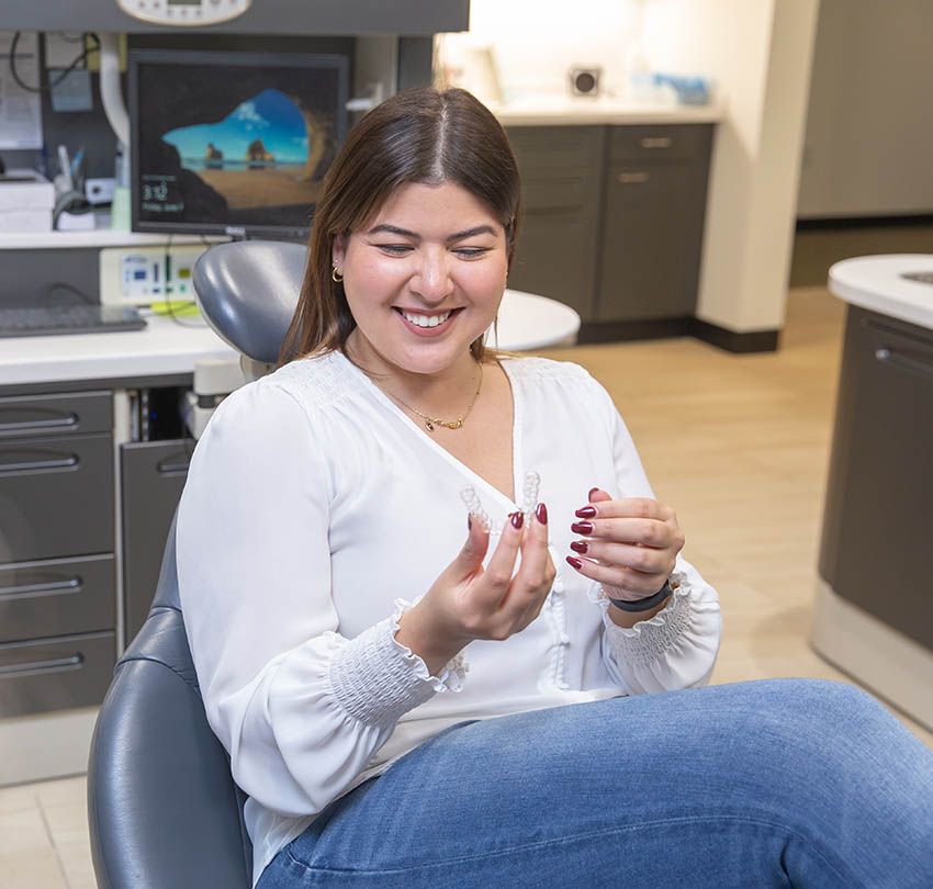 Patient holding invisalign clear aligners at Boulder Dental Designs in Boulder, CO